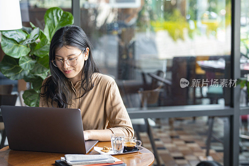 亚洲女大学生在咖啡馆用笔记本电脑远程学习