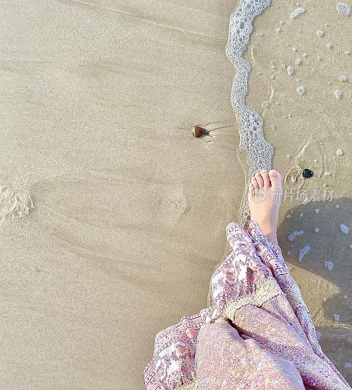 赤脚走在海滩海岸线粉红色的花裙子