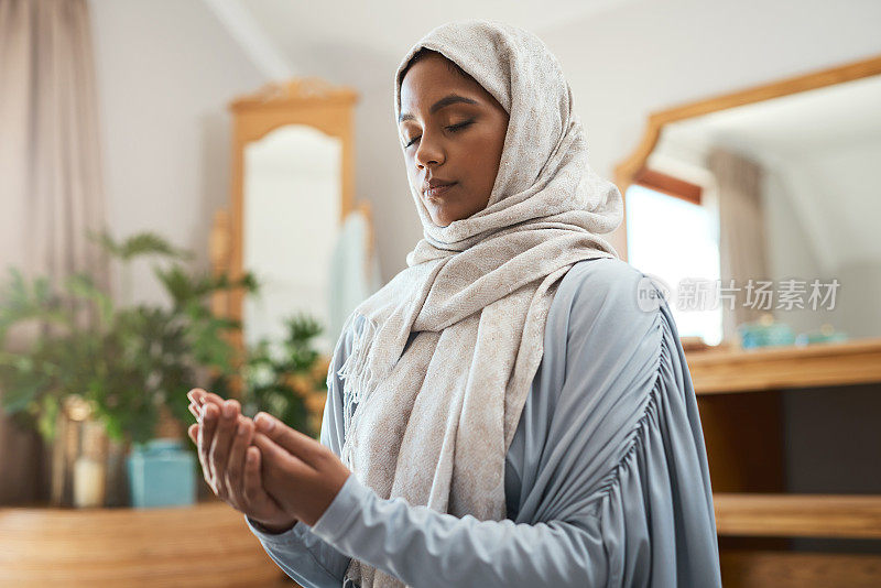 一个年轻的穆斯林妇女在家里的休息室祈祷