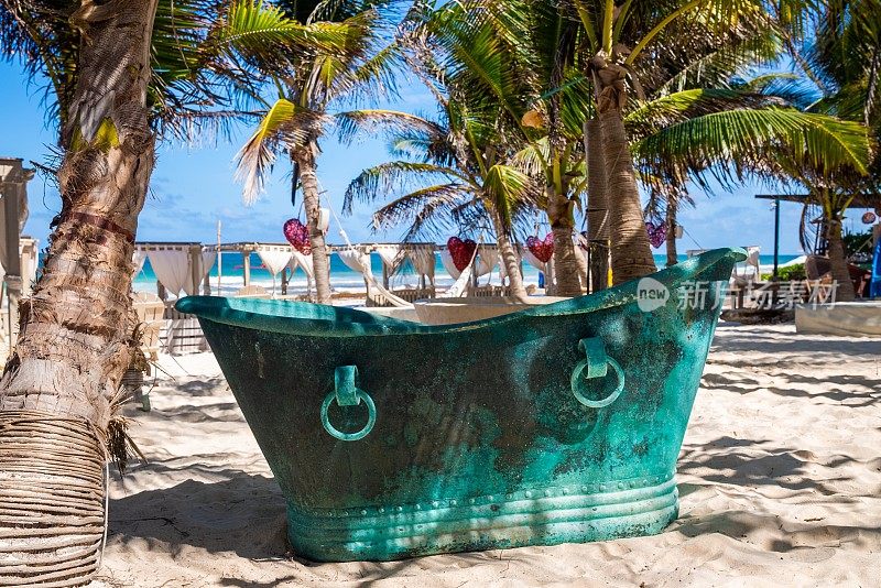 复古风格的金属浴缸在海滩度假村与心脏形状的艺术品挂在树上