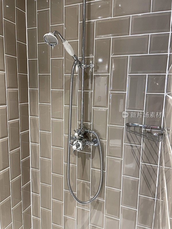 现代浴室的形象，独立的淋浴间，光滑的棕色瓷砖墙，现代定向淋浴头挂在墙上，镀铬的洗漱用品架