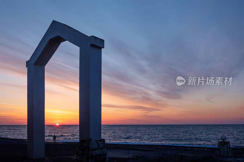 海岸上美丽的日落，海岸上的拱门，海岸上一个男人的剪影
