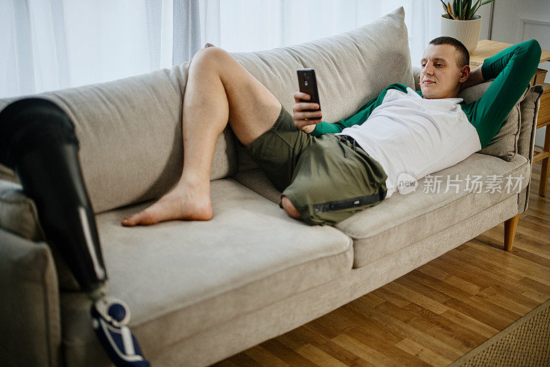 男性假肢截肢者在家用手机放松