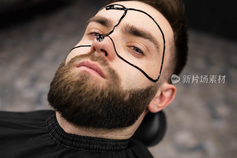 男士化妆面膜用黑色面膜滋润脸部，护理肌肤。