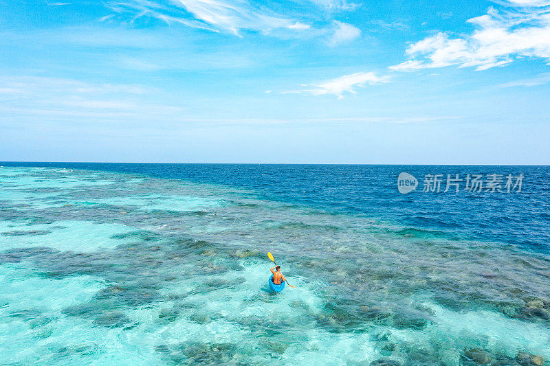 在热带海洋上划着皮艇的年轻人