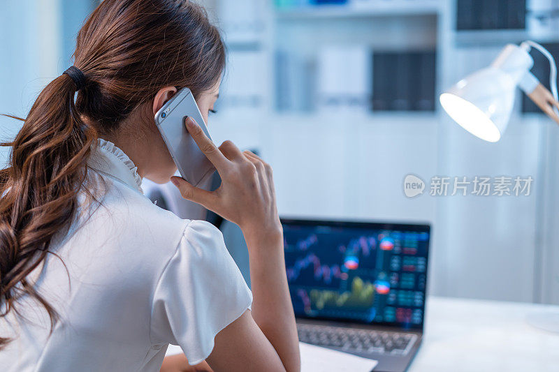 亚洲经纪交易员在办公室提供投资股票市场的咨询和图表。职业女性呼叫中心利用手机在工作场所深夜对客户进行理财管理和分析。