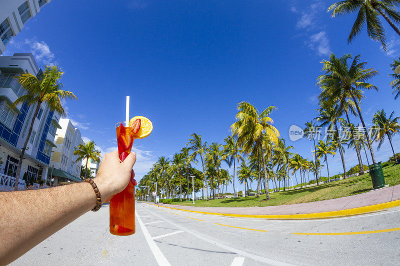 一名年轻的旅行男性一边享受他的假期，一边喝着鸡尾酒，在海洋大道，南海滩，迈阿密海滩，迈阿密，南佛罗里达，美国