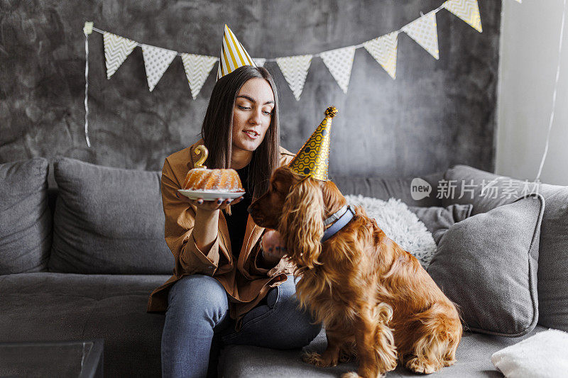 微笑的女人和她的狗在家里庆祝她的狗生日。