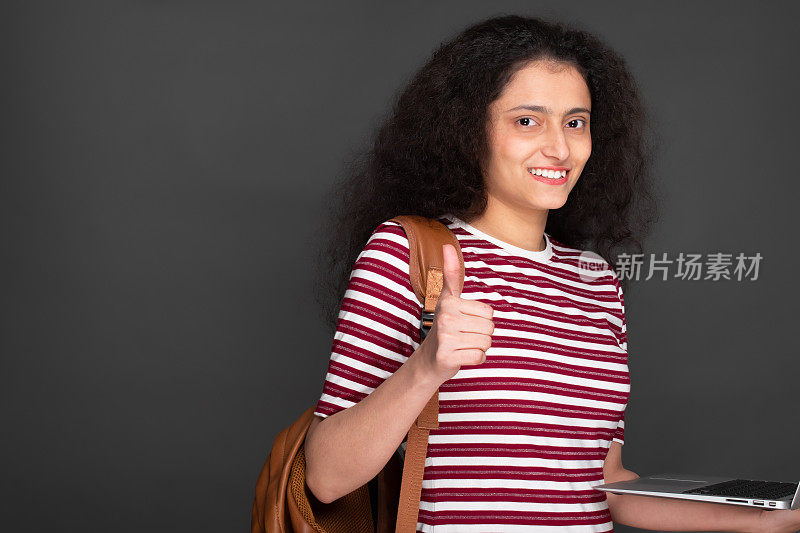 年轻的女学生使用笔记本电脑和显示大拇指向上的股票照片