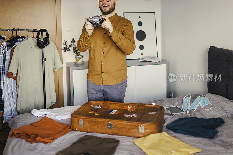 英俊的男人在酒店预订，准备旅行假期整齐地打包行李的衣服和配件