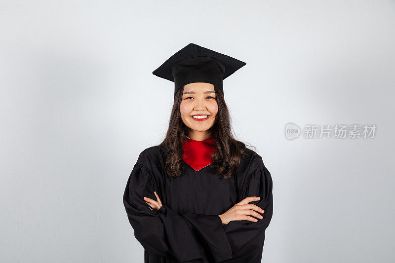 微笑的研究生，戴着学士帽，穿着学士服，背景是白色的