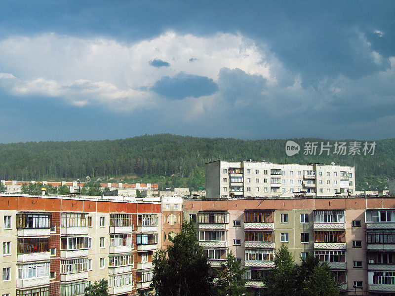 俄罗斯的高层住宅，背景是树木繁茂的山丘和多云的天空