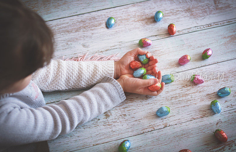 复活节。孩子们的手在木桌上拿着巧克力复活节彩蛋