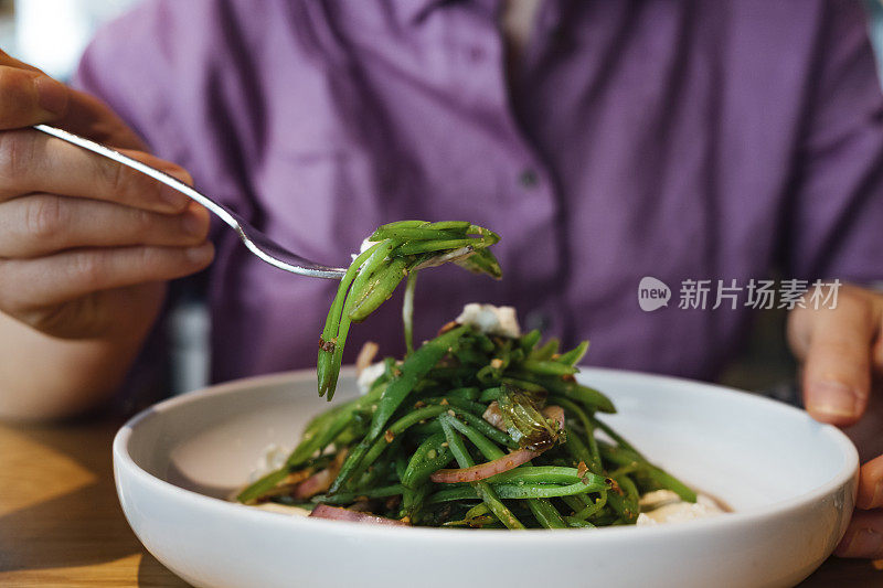 一名匿名女子在餐厅吃午餐的裁剪照片