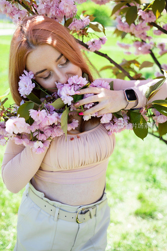 盛开的樱花的树。夏日时尚与美丽。女士在公园散步。粉红色的樱花。