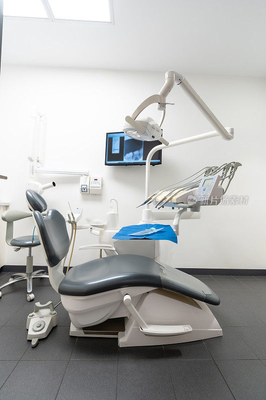 现代牙科实践。牙科椅，医疗灯，没有人的牙科诊所。垂直图