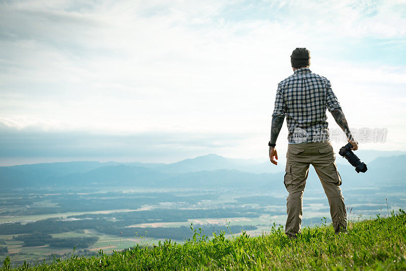 风景摄影师在美丽的绿色大自然中，站在山顶。