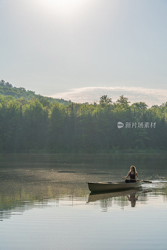 一个女人在清晨划独木舟。