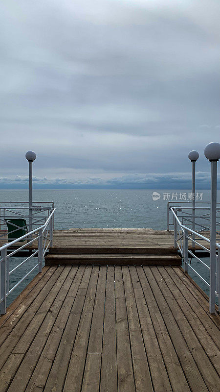 在阳光明媚的日子里，海上的木制码头通向水面，供游客旅行和休息