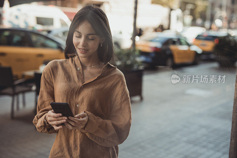 一个小女孩，走在西班牙首都的街道上，用着手机