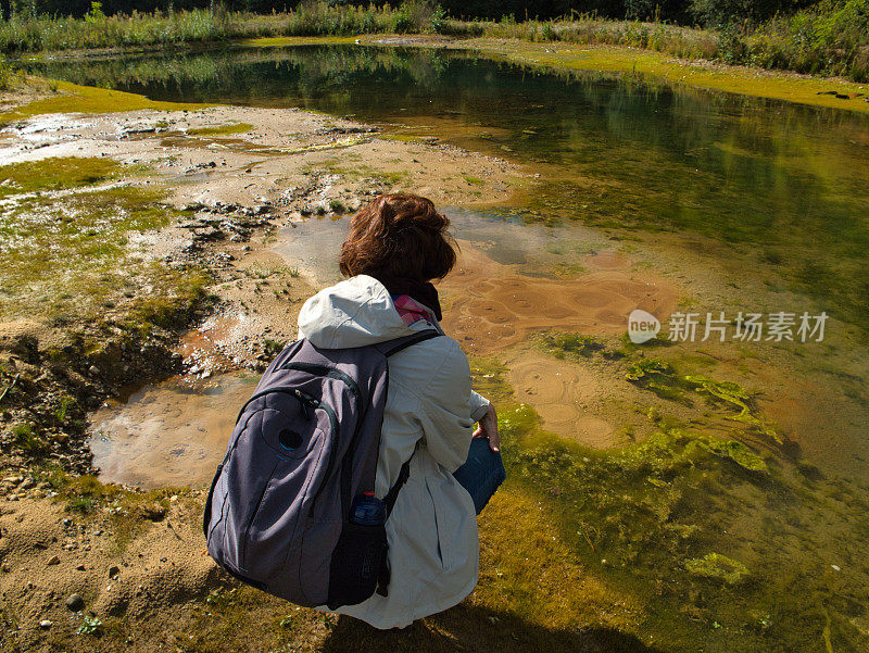 一名徒步旅行者在透明的泻湖上看着沙子上的泡泡。俯视图