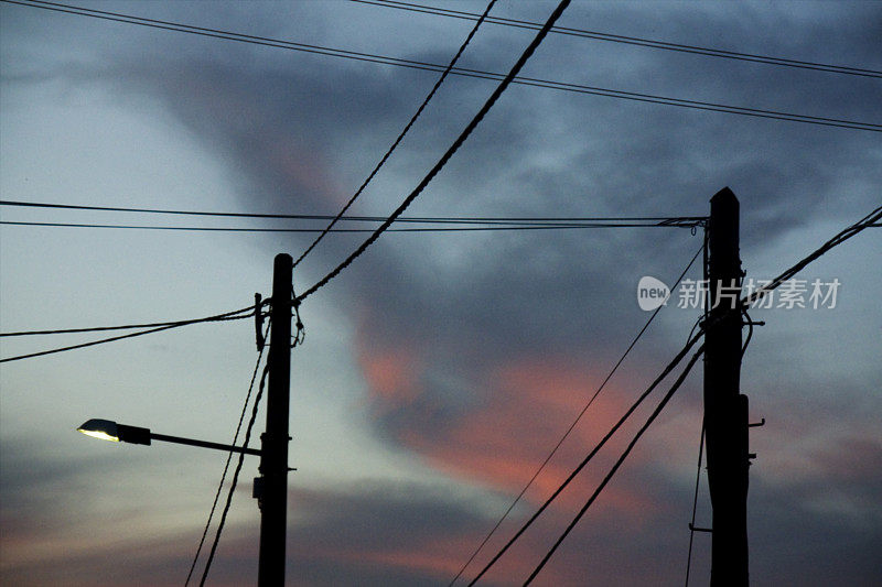 路灯，电线杆和电缆剪影和黄昏背景。