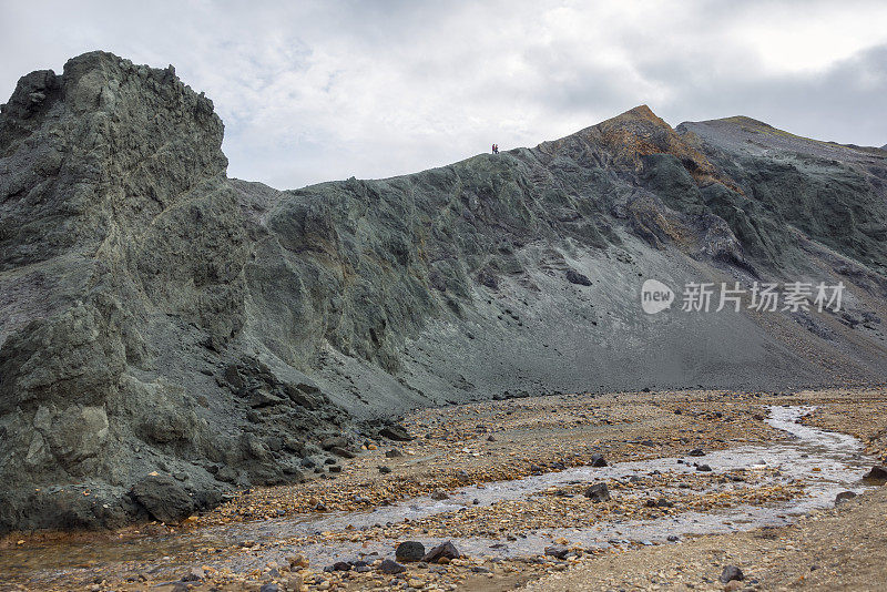 流经熔岩田和火山山脉。徒步旅行者正在爬上一座火山。