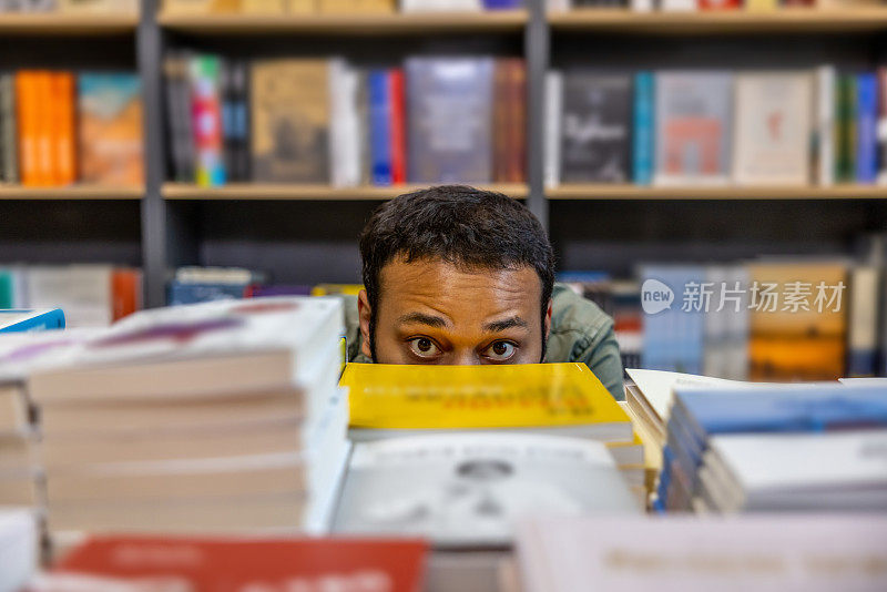 年轻的黑皮肤男人躲在书架后面