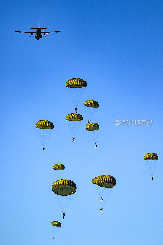 在晴空万里的蓝天上，军队伞兵从空军飞机上跳伞。