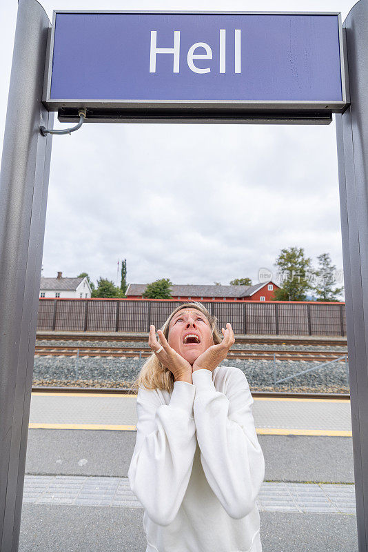 挪威火车站，一个女人在地狱标志下做鬼脸