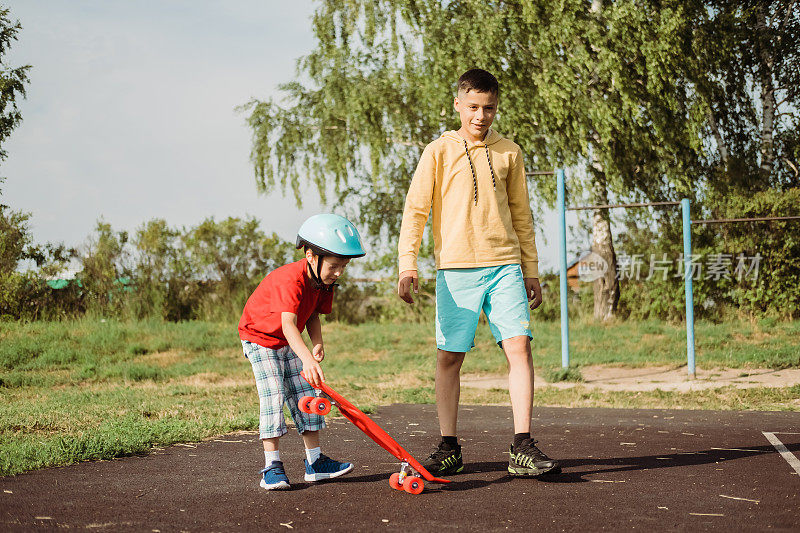 哥哥教弟弟玩滑板。男孩们在玩滑板。户外快乐的家庭。健康、真实、平衡感和冷静。