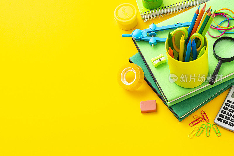 返校概念:绿色的学习用品在黄色的背景上拍摄，并留有复制空间