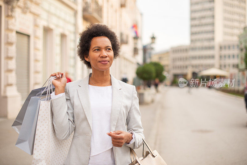 一个快乐的女人在城市里享受购物的画像