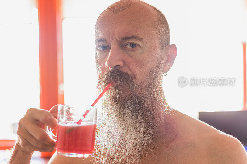 长胡子的中年酷男喝着西瓜汁