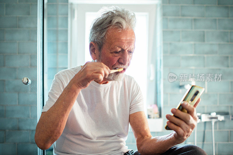 老人在浴室边刷牙边用智能手机