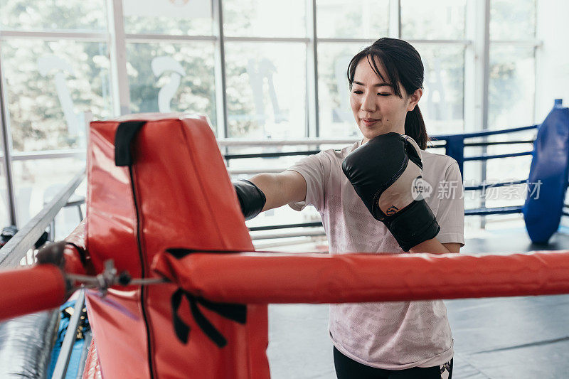 在训练馆里练习自由搏击的亚洲女子