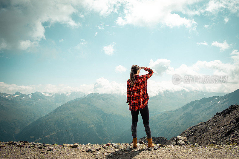 一位妇女站在山顶上欣赏山谷的景色。