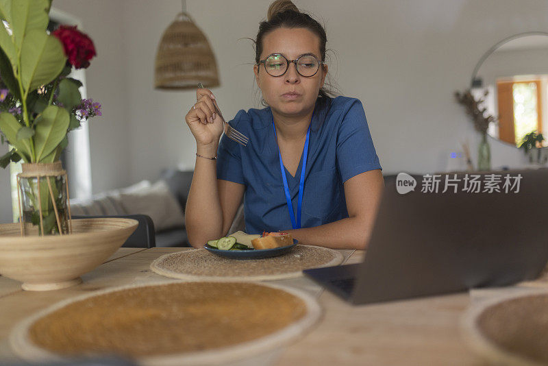 上班前，护士在家吃早餐，坐在餐桌前用笔记本电脑