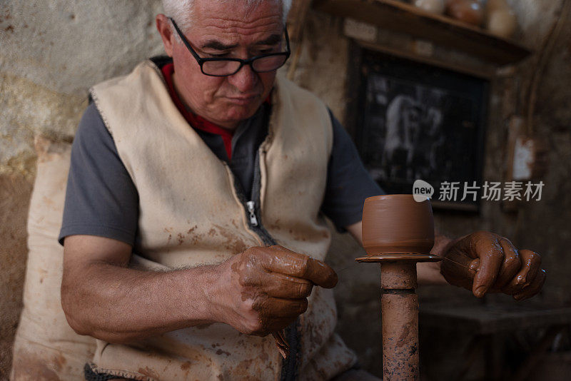 一位老人正在制作一个陶杯