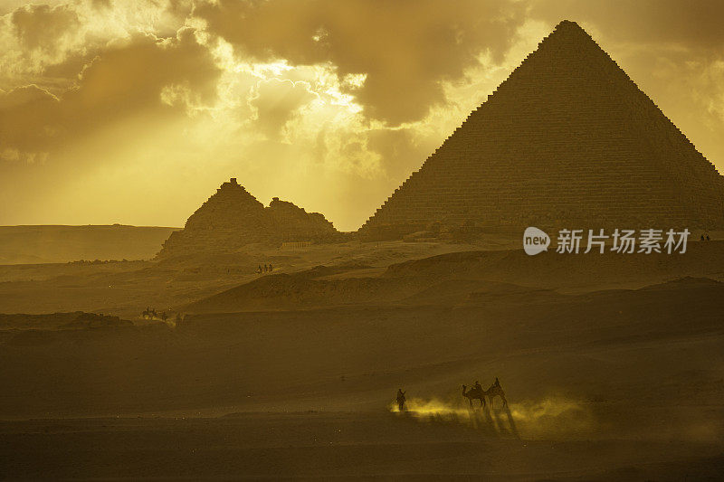 吉萨金字塔和日出时的骆驼车夫。
