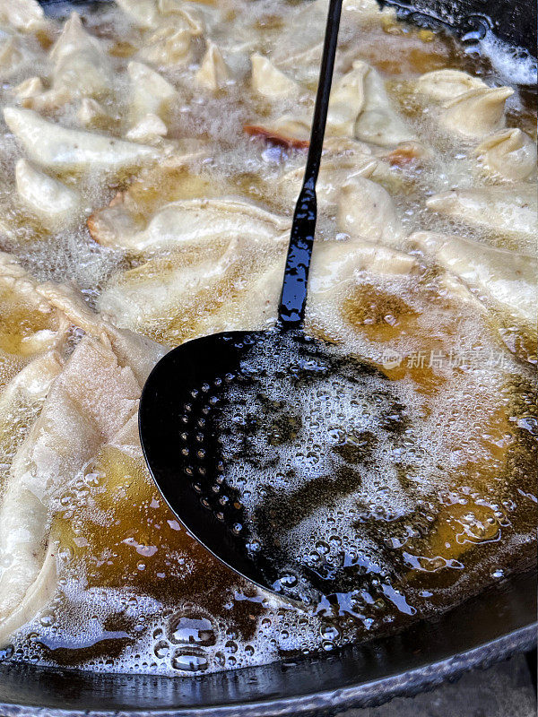 全帧图像的samosas在karahi(印度锅)中油炸，冒泡的热油，开槽的勺子，印度街头小吃摊，不健康的饮食，高架视图