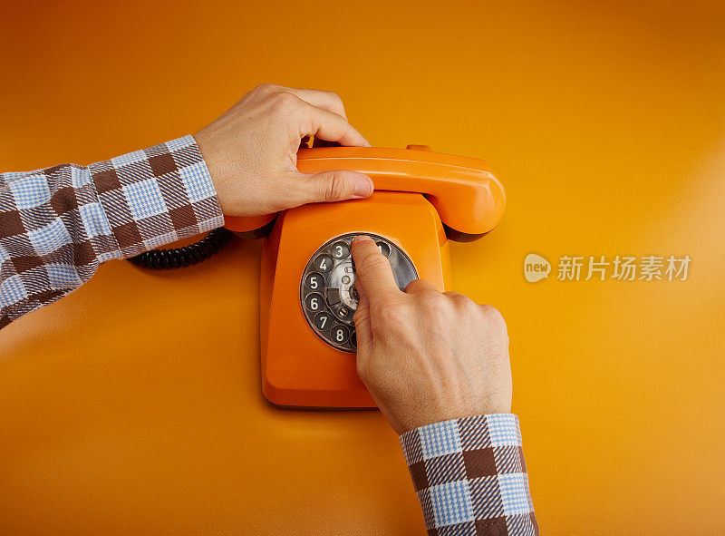 打个电话。拿着一个老式的电话听筒。一个橙色的复古电话接收机手持手持桔黄色的背景