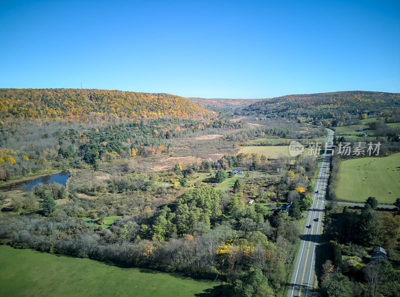 在乡村公路上行驶的汽车，背景是山脉(秋天，秋天的景色，树木变色)交通鸟瞰图(无人机镜头，从高空拍摄，鸟瞰图)