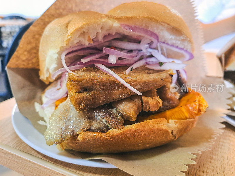 秘鲁猪肉脆皮三明治配洋葱和红薯片。秘鲁猪皮三明治，配洋葱和红薯片。