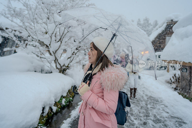 美丽的女游客享受他们的旅行白川古村在日本的冬天厚雪