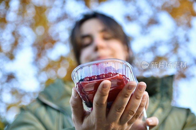 女孩拿着一个塑料盒子，里面装着浆果