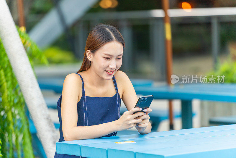 年轻的亚洲妇女在户外公园方便地进行数字银行信用卡交易