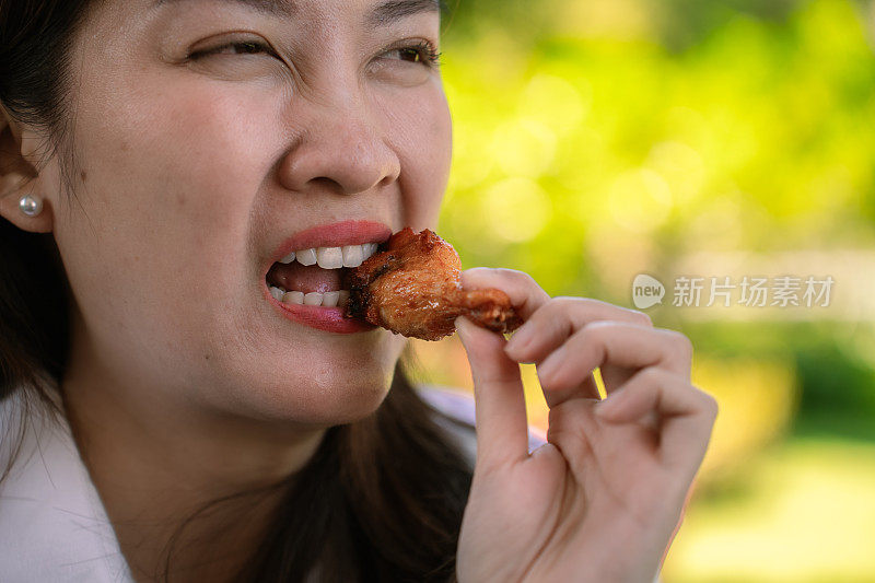 近距离拍摄的亚洲女性用牙齿咀嚼坚硬的食物，并表现出因牙痛而焦虑的面部表情。