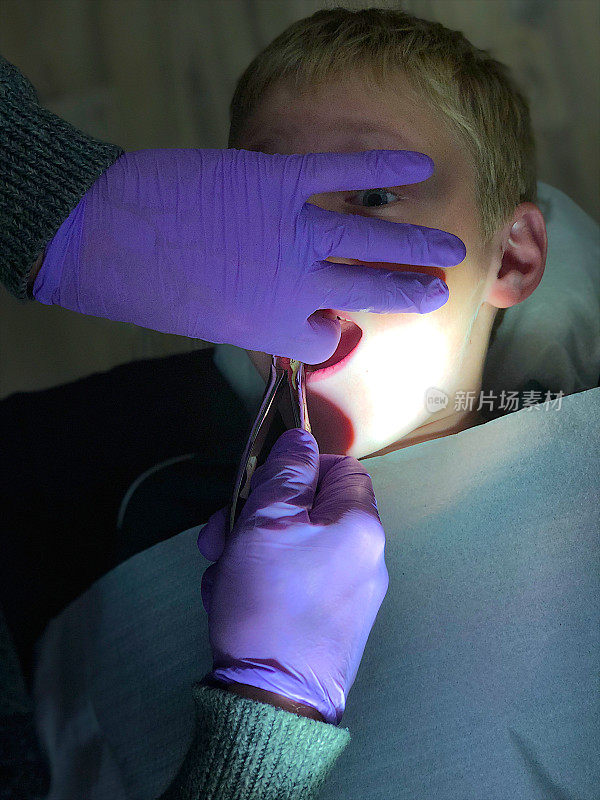 牙医在拔受惊的男孩的牙