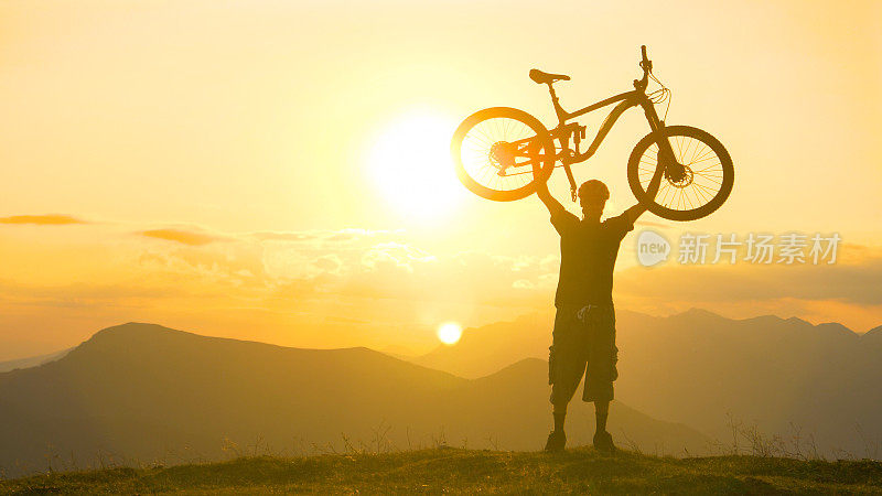拷贝空间:一名兴奋的男子在一次成功的旅行后将自行车举过头顶。